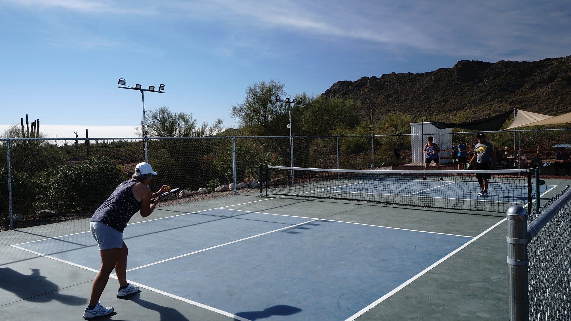 Two active adults playing pickleball on a resort court with Picacho Peak behind them.