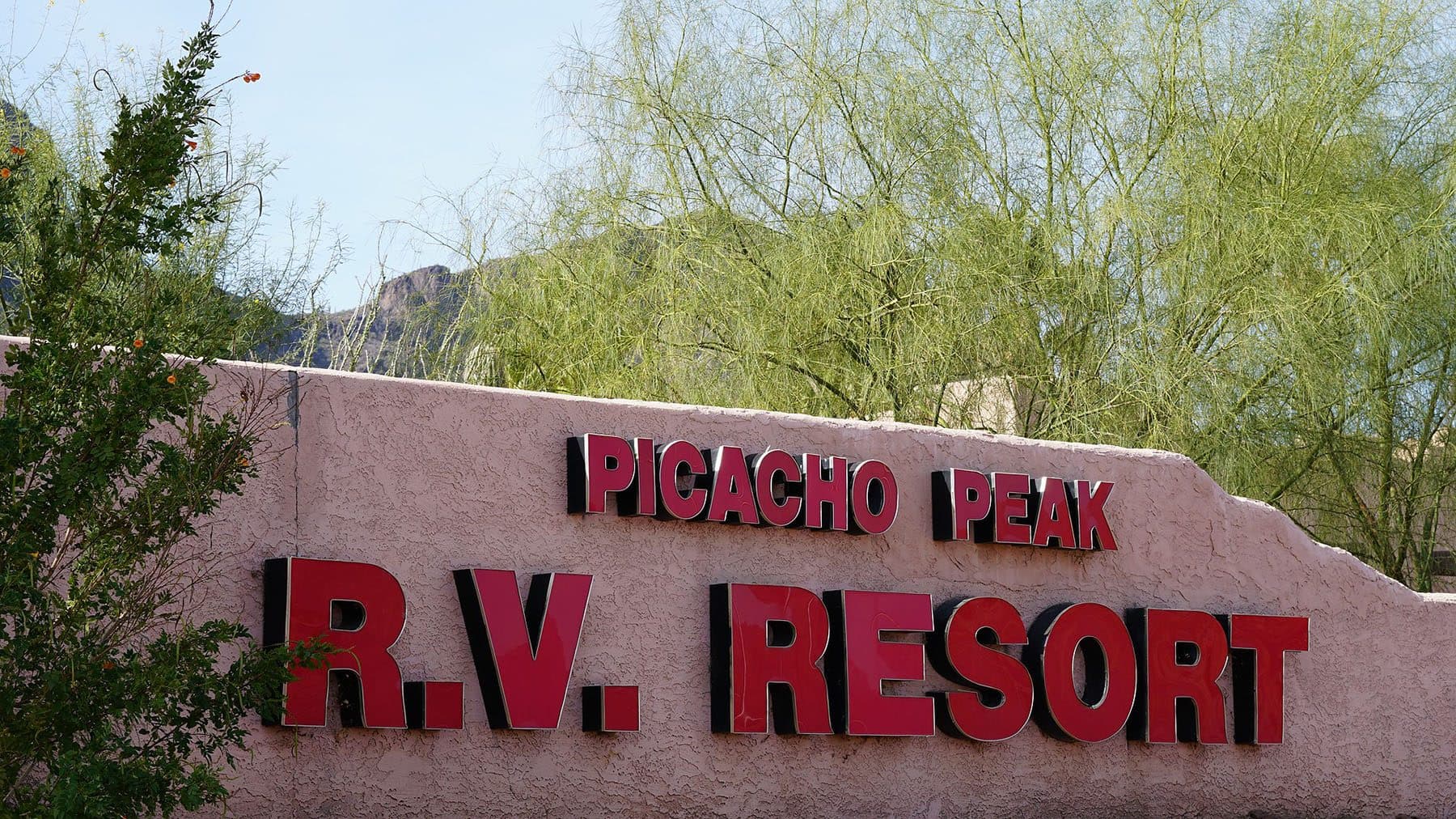 The Picacho Peak R.V. Resort entrance sign framed by desert trees.